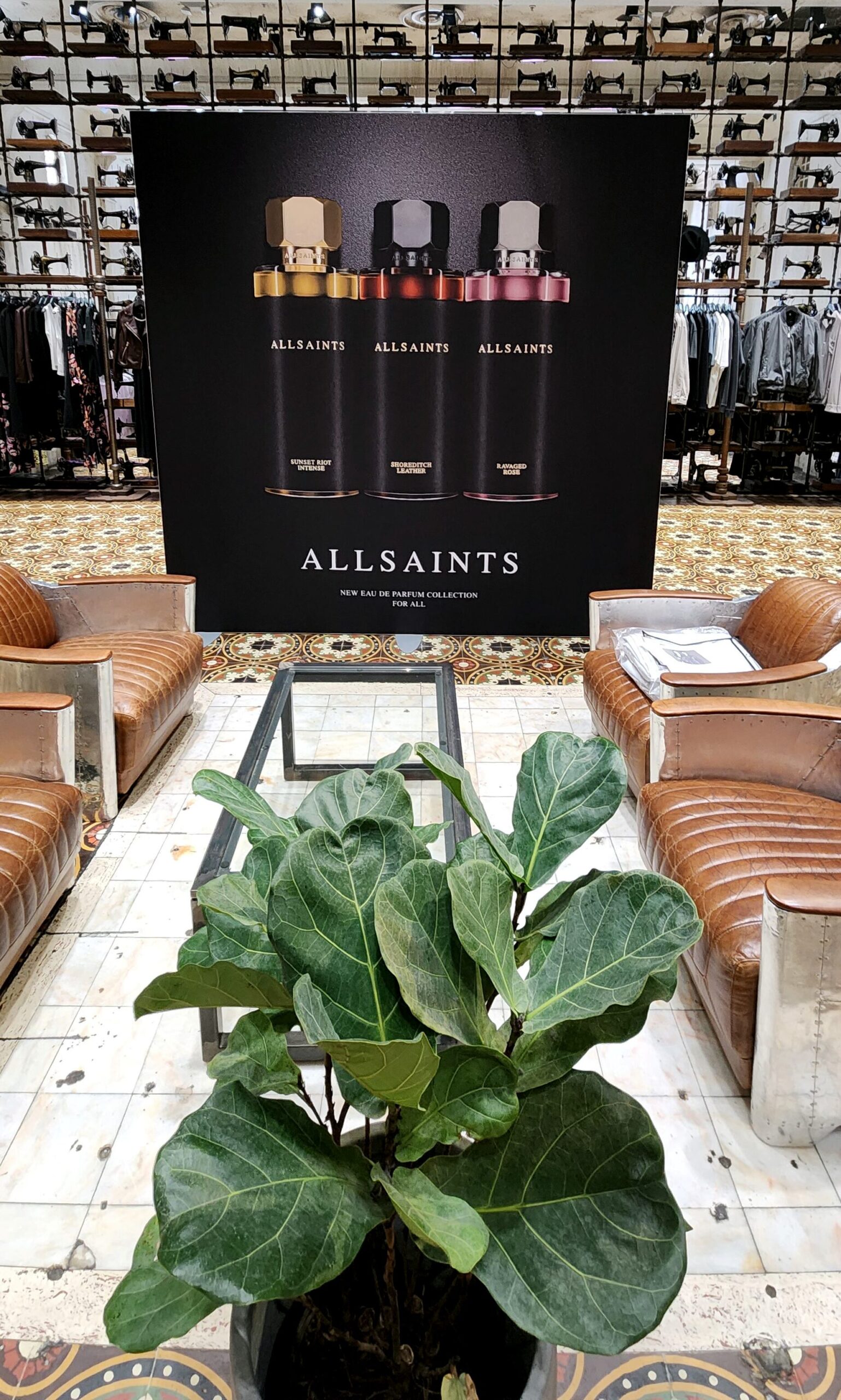 AllSaints Eau de Parfum collection promotional poster display inside an AllSaints retail store on Lincoln Road, featuring three fragrance bottles